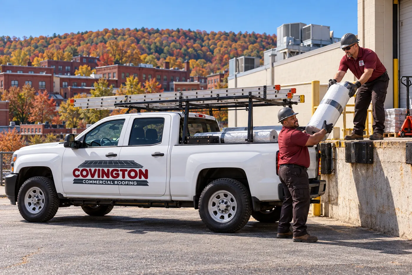 Roofing truck and crew staged beside a commercial building before work starts